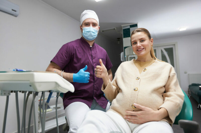 Dentist doctor and pregnant womansmiling, thumbing up looking at camera after dental check-up